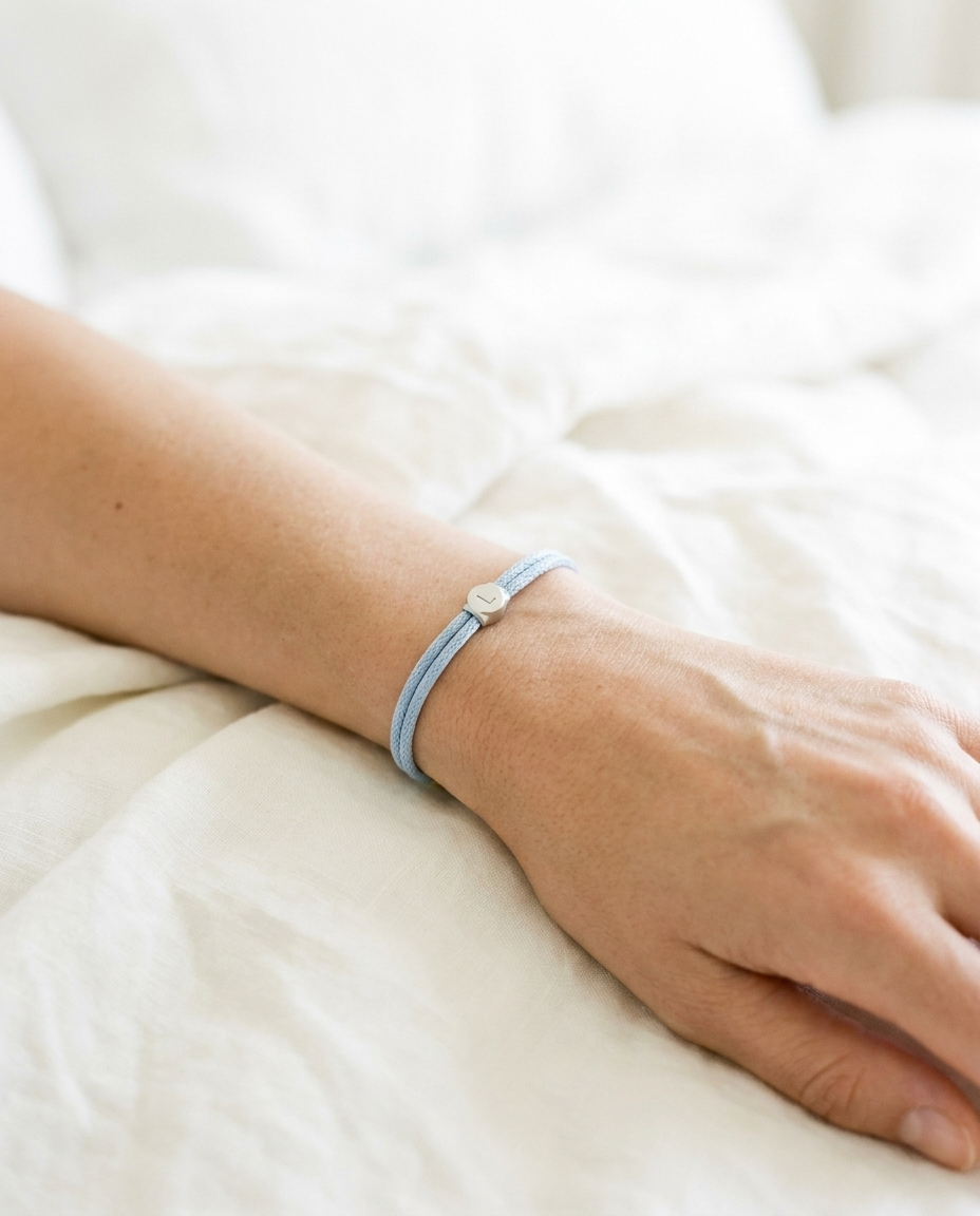 Lükii CLASSIC Sky band on wrist resting on cream linen in soft morning light