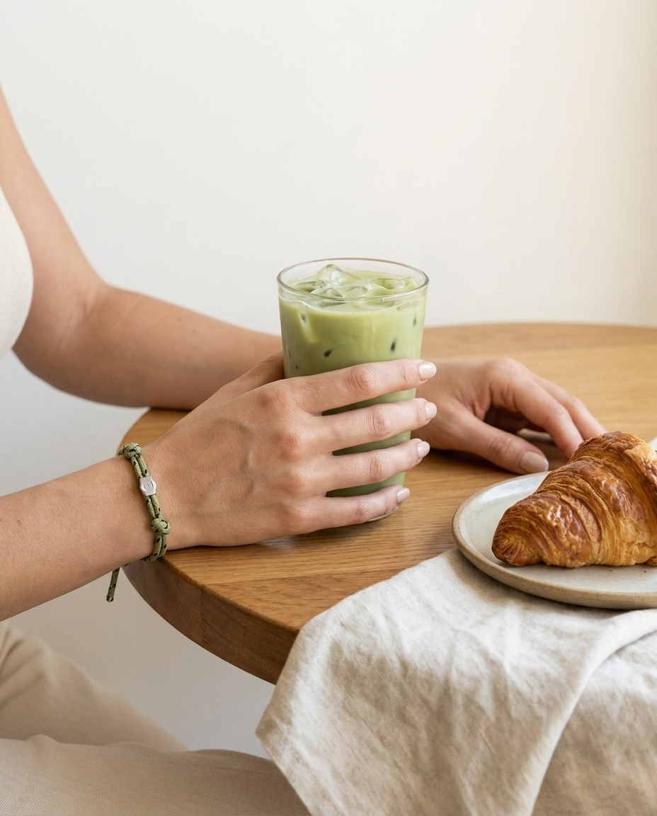 Lükii EVERYDAY Olive band worn at a café table with iced matcha