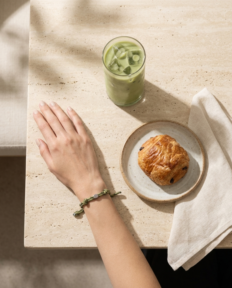 Lükii EVERYDAY Olive band aerial flat-lay on café table with matcha and croissant